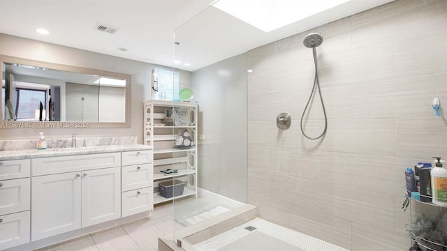 bathroom with a tile shower, tile floors, and vanity