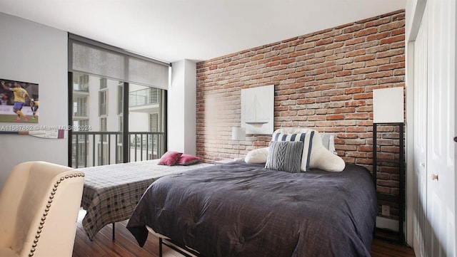 bedroom with dark hardwood / wood-style flooring and brick wall