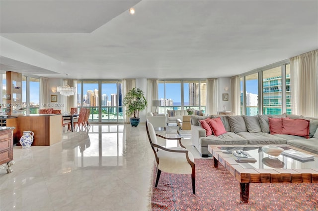 living room featuring an inviting chandelier, a wall of windows, and a healthy amount of sunlight