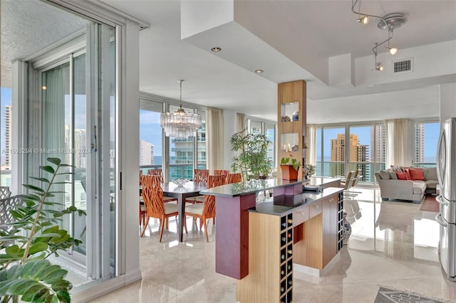 kitchen with stainless steel fridge, a healthy amount of sunlight, a chandelier, and decorative light fixtures