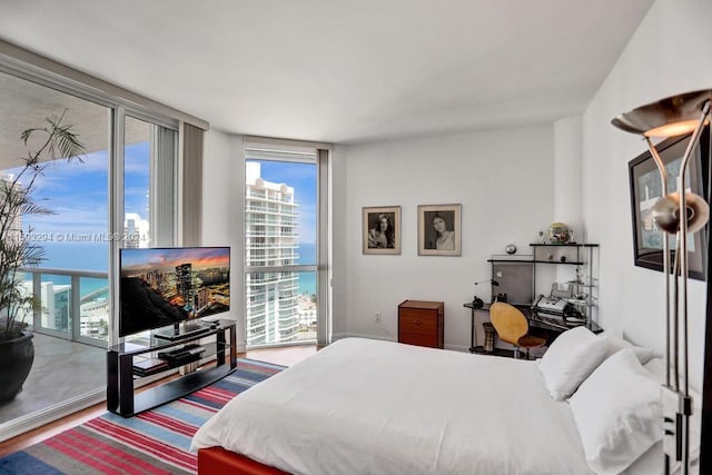 bedroom featuring expansive windows, access to outside, and wood-type flooring