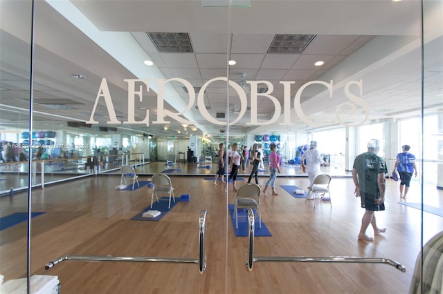 exercise room featuring hardwood / wood-style floors, a drop ceiling, and expansive windows