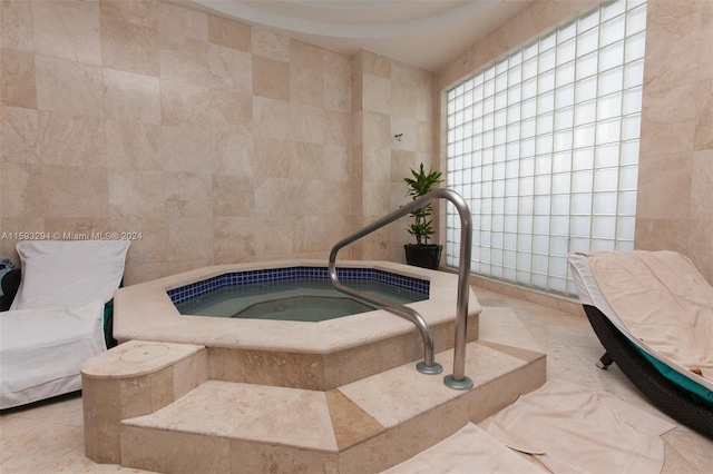 interior space with tile walls, a hot tub, and light tile patterned floors