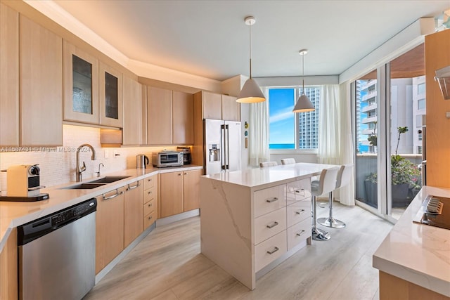 kitchen with a center island, hanging light fixtures, light hardwood / wood-style flooring, stainless steel appliances, and backsplash