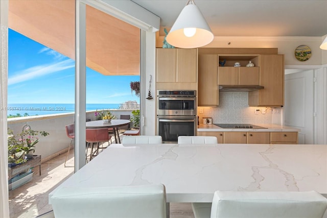 kitchen featuring decorative light fixtures, light brown cabinets, a water view, tasteful backsplash, and stainless steel double oven