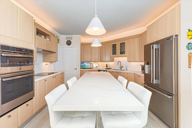 kitchen featuring light stone countertops, backsplash, a kitchen island, a kitchen bar, and appliances with stainless steel finishes