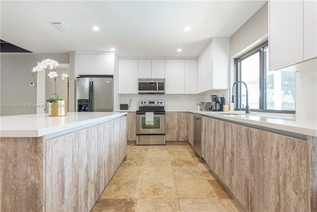 kitchen featuring a kitchen island, light tile floors, sink, white cabinets, and appliances with stainless steel finishes