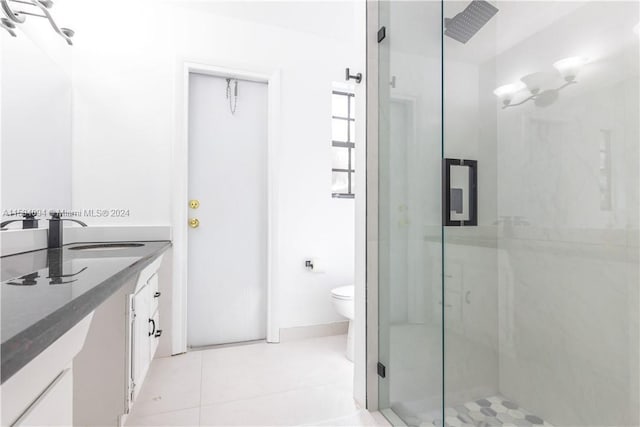 bathroom featuring tile flooring, vanity, toilet, and a shower with door