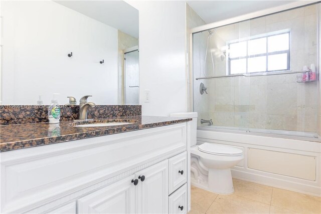 full bathroom featuring tile flooring, enclosed tub / shower combo, toilet, and large vanity