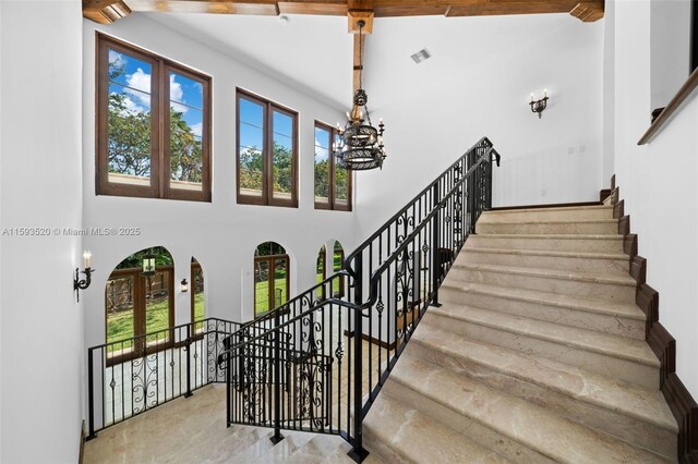 stairway with beamed ceiling, a high ceiling, and tile flooring