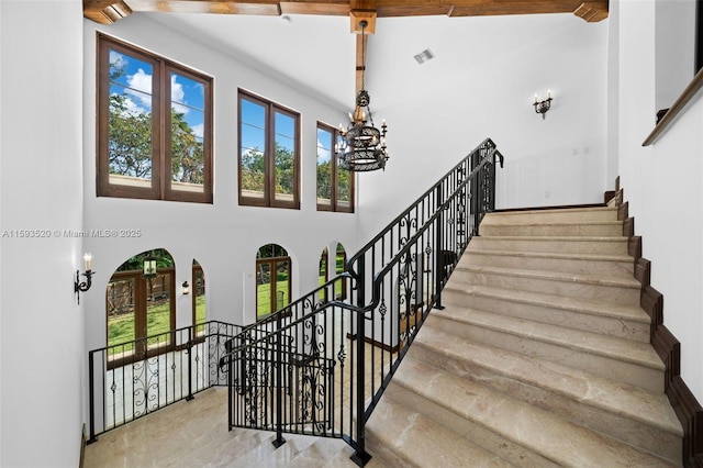 stairs with a towering ceiling and a chandelier