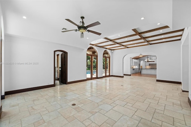 unfurnished living room featuring ceiling fan with notable chandelier, coffered ceiling, and beam ceiling