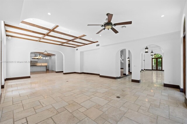 tiled empty room with coffered ceiling, ceiling fan with notable chandelier, and beamed ceiling