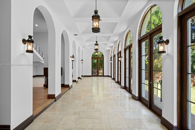 interior space featuring tile floors, coffered ceiling, french doors, and a wealth of natural light