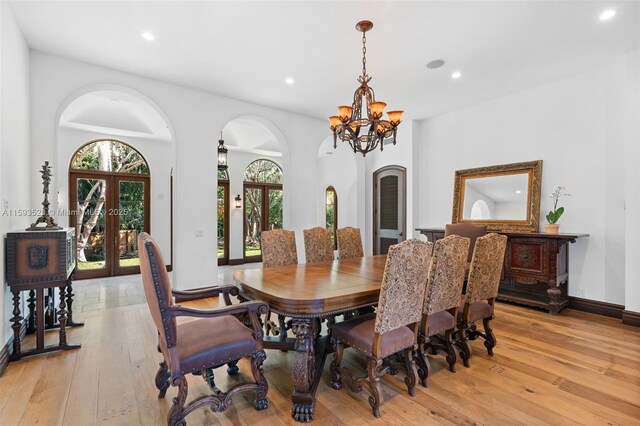 dining area featuring french doors, light wood-type flooring, and a chandelier