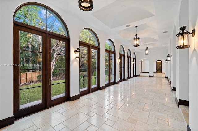 interior space with a wealth of natural light, a high ceiling, a tray ceiling, and light tile floors