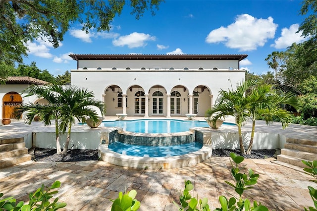 back of property with a pool with hot tub, french doors, and a patio