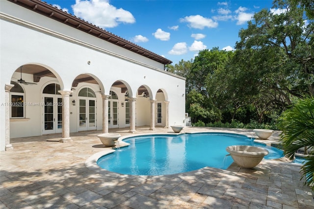 view of swimming pool with pool water feature, a patio area, and french doors