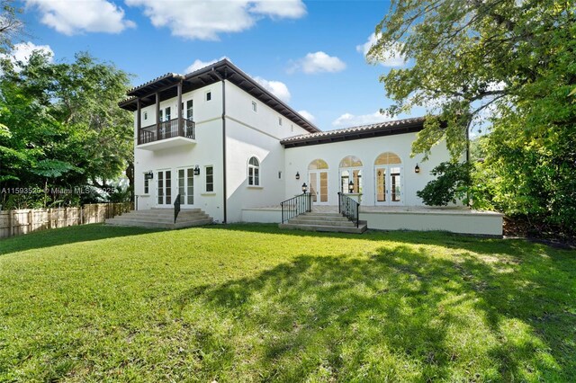 back of house with a balcony, french doors, and a lawn