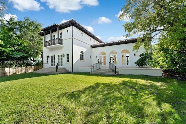 rear view of property with a yard, french doors, and a balcony