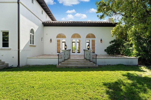 view of exterior entry with french doors and a lawn