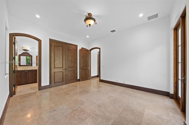 unfurnished bedroom featuring ensuite bathroom and light tile flooring