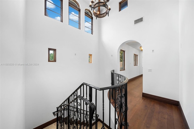 staircase with wood-type flooring, a high ceiling, and a chandelier