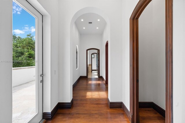 hallway with a healthy amount of sunlight and dark hardwood / wood-style flooring