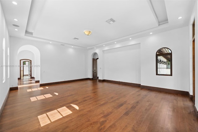 empty room with a tray ceiling and dark hardwood / wood-style flooring