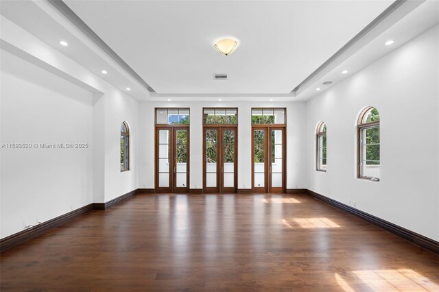 empty room with a tray ceiling and dark hardwood / wood-style floors