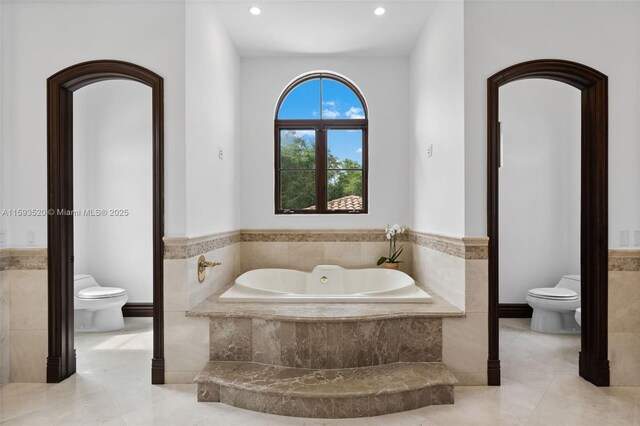 bathroom featuring tile floors, a relaxing tiled bath, and toilet