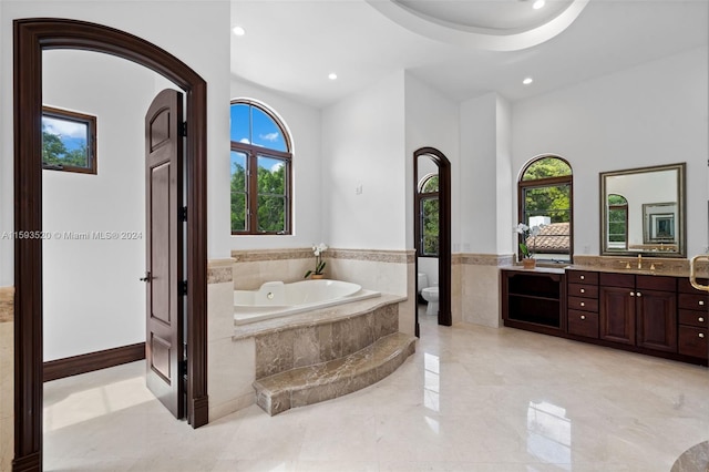 bathroom featuring tile flooring, tiled tub, a wealth of natural light, and vanity