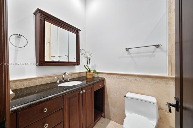 bathroom with tile floors, tile walls, toilet, and vanity