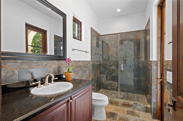 bathroom with tile flooring, tasteful backsplash, walk in shower, toilet, and vanity