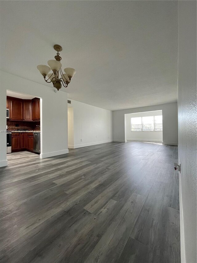 unfurnished room with a chandelier, a textured ceiling, and dark hardwood / wood-style floors