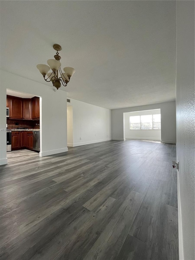 unfurnished living room with dark wood finished floors, baseboards, and an inviting chandelier