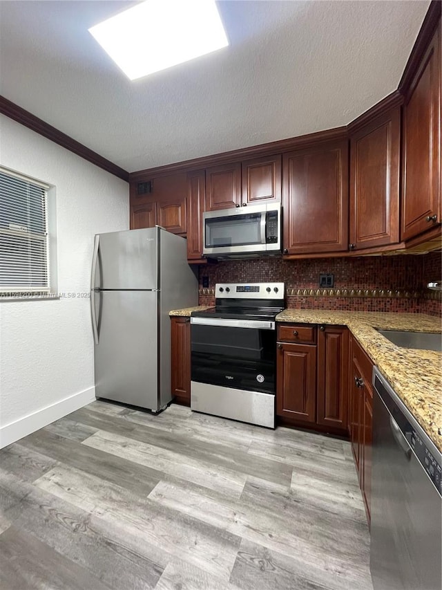 kitchen featuring backsplash, crown molding, light wood-style flooring, appliances with stainless steel finishes, and a sink