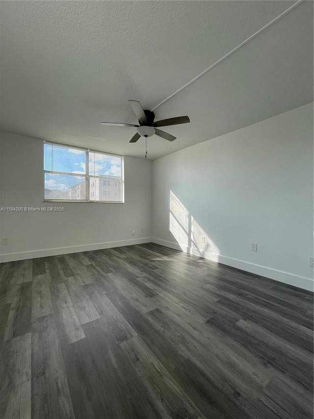 unfurnished room with baseboards, a textured ceiling, dark wood-style floors, and a ceiling fan