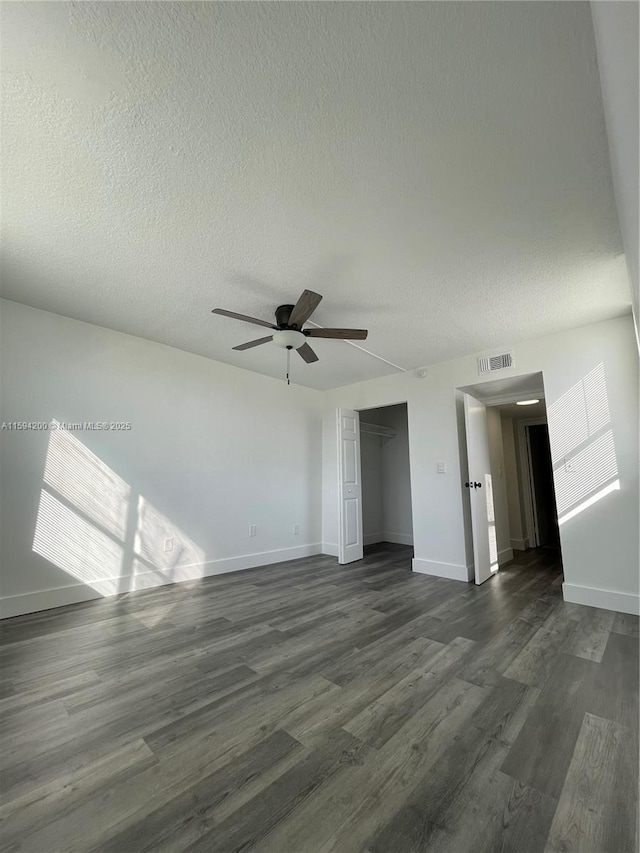 unfurnished living room with visible vents, baseboards, dark wood-type flooring, and ceiling fan