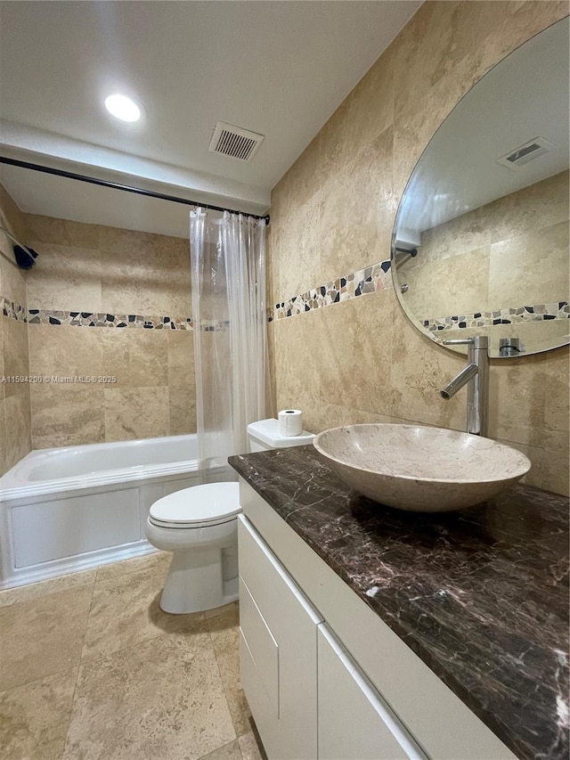 full bath featuring visible vents, tile walls, toilet, shower / tub combo, and vanity