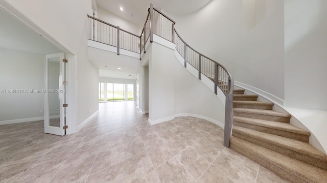 staircase featuring a high ceiling and light tile floors