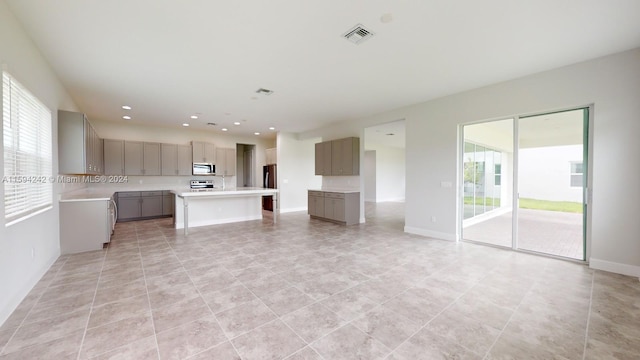 kitchen with gray cabinetry, stove, a kitchen island, and light tile floors