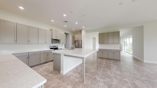 kitchen featuring an island with sink, a breakfast bar area, electric stove, sink, and light tile flooring