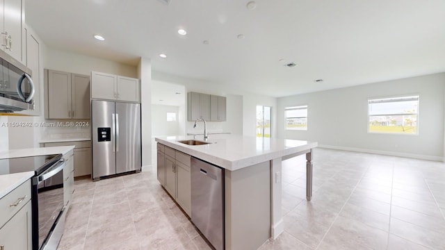 kitchen featuring a center island with sink, appliances with stainless steel finishes, sink, and light tile flooring