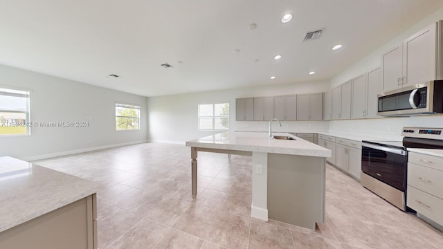 kitchen featuring light tile floors, sink, a center island with sink, and stainless steel appliances