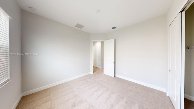 unfurnished bedroom featuring a closet and light carpet