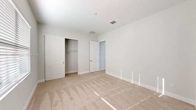 unfurnished bedroom featuring a closet and light carpet