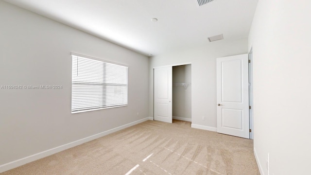 unfurnished bedroom with a closet and light carpet