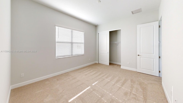 unfurnished bedroom featuring light colored carpet and a closet