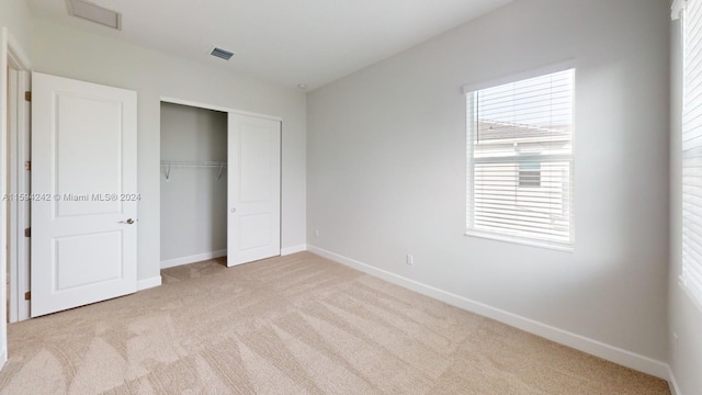 unfurnished bedroom featuring light carpet and a closet